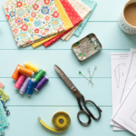 Flat lay of colorful sewing supplies, paper patterns, and a finished sewing project on a bright workspace.